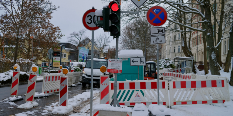 Zu sehen ist die Baustelle an der Weststraße/ Ecke Michaelstraße mit roter Ampel und Schild "Fußgänger Straßenseite wechseln"